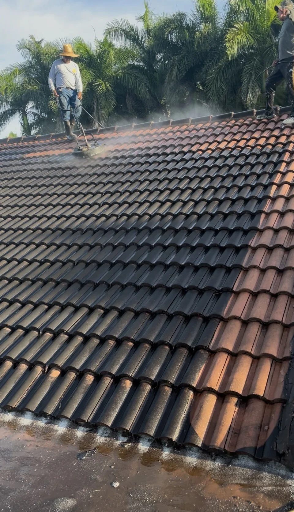 Crew pressure-washing a barrel tile roof, showing clean tile next to dirty tile