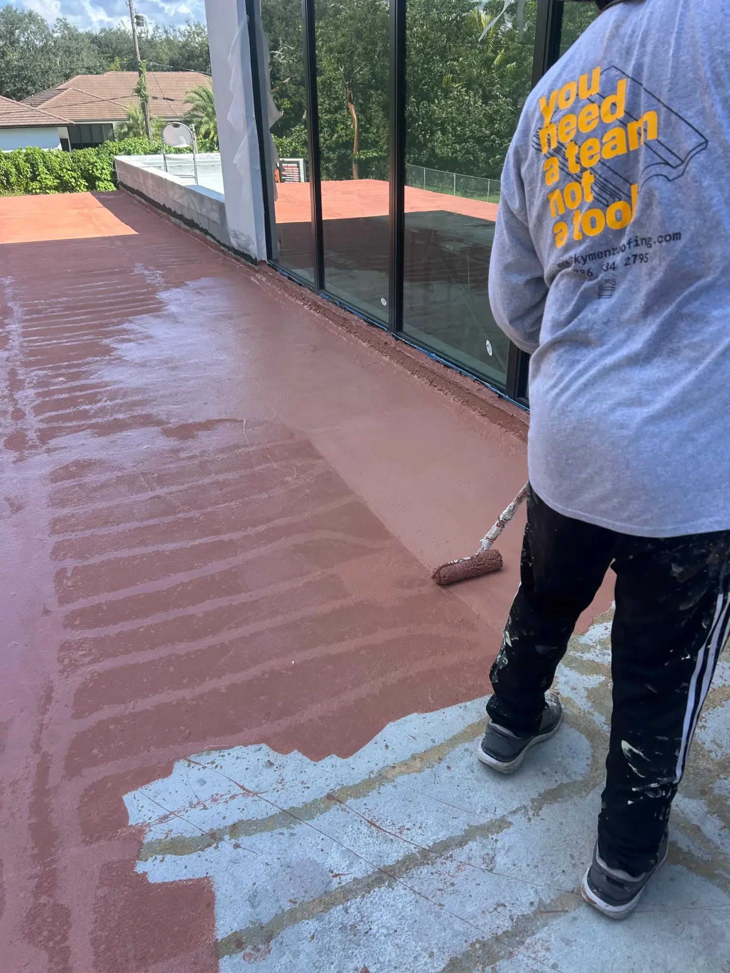 Equipo de Skymen Roofing aplicando con rodillo un recubrimiento impermeable en un techo plano