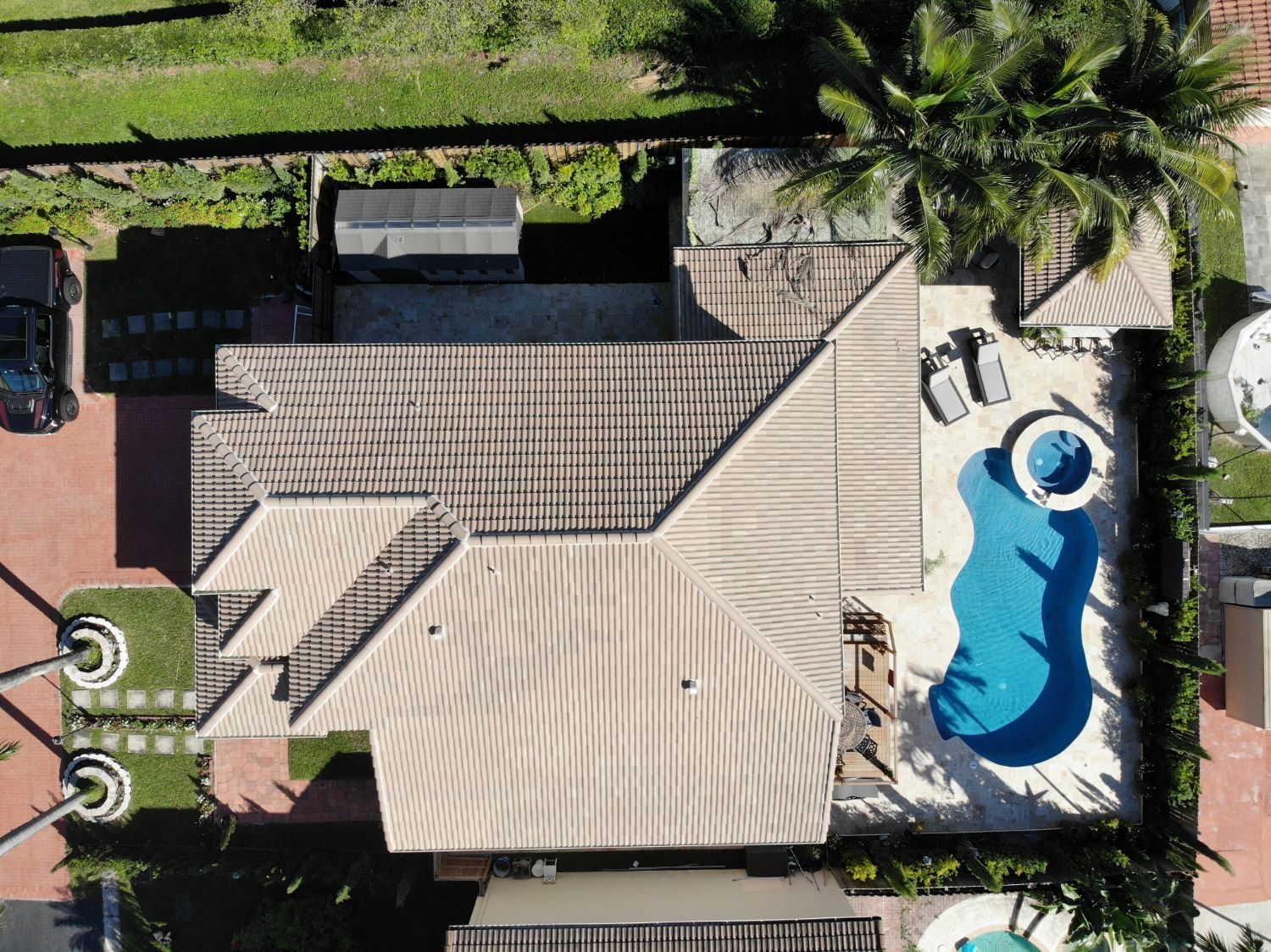 Aerial view of a tan low-profile flat concrete tile roof on a home with a pool